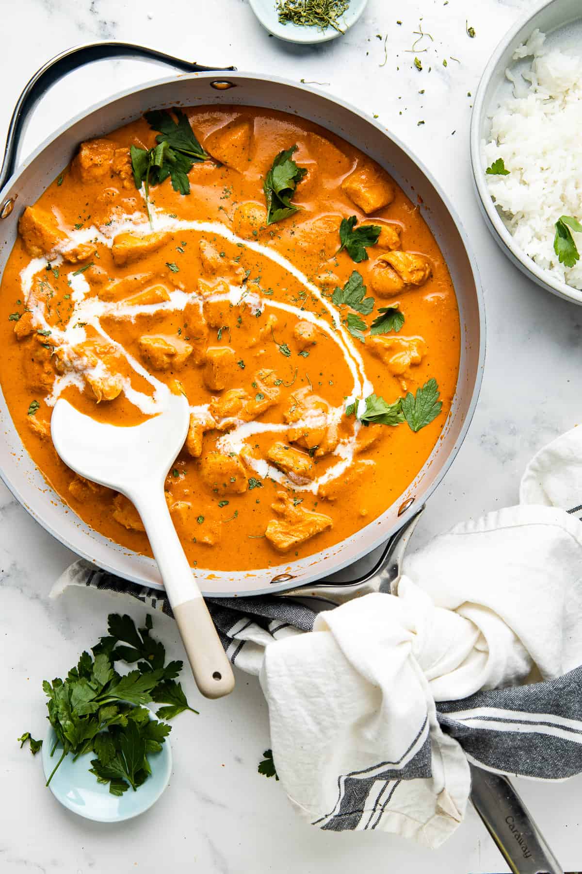 Butter chicken served in a skillet, garnished with cilantro and served with rice.