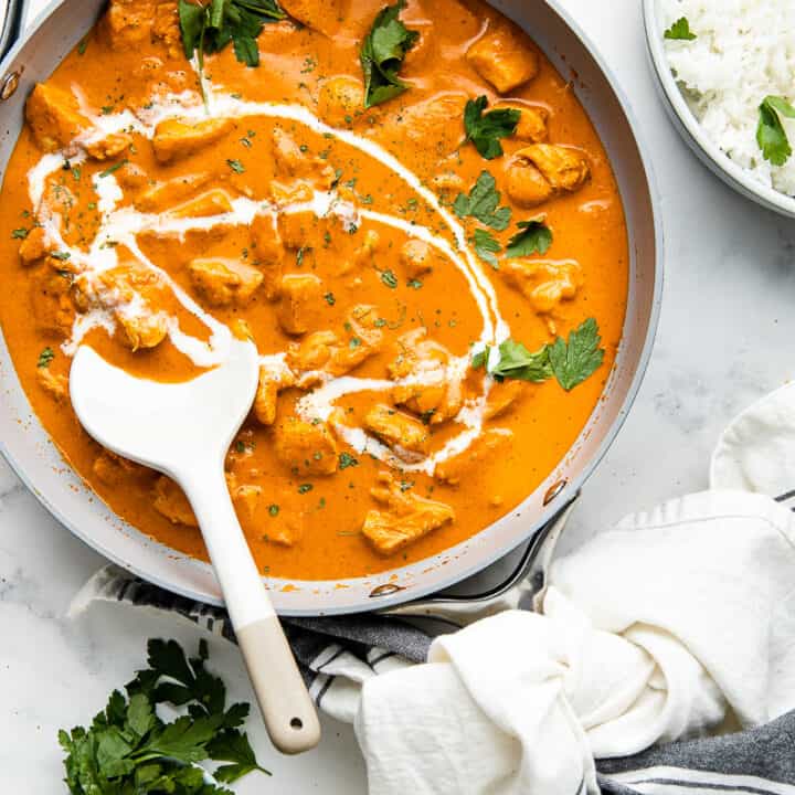 Flat lay photo of a skillet with Murgh Makhani, placed on a marble countertop