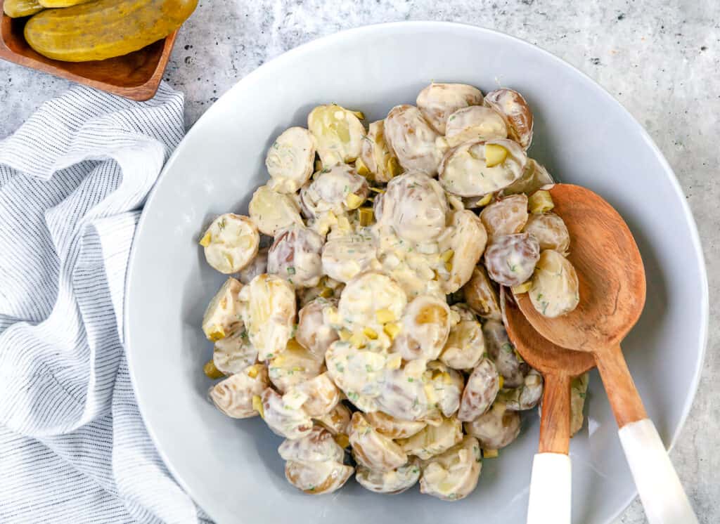 Dill pickle potato salad in a large serving bowl, with serving spoons