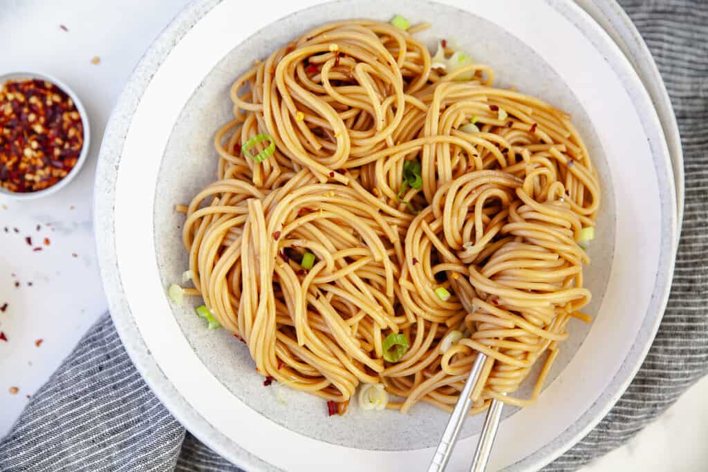 Spicy chilli garlic noodles plated in a bowl, with chopsticks
