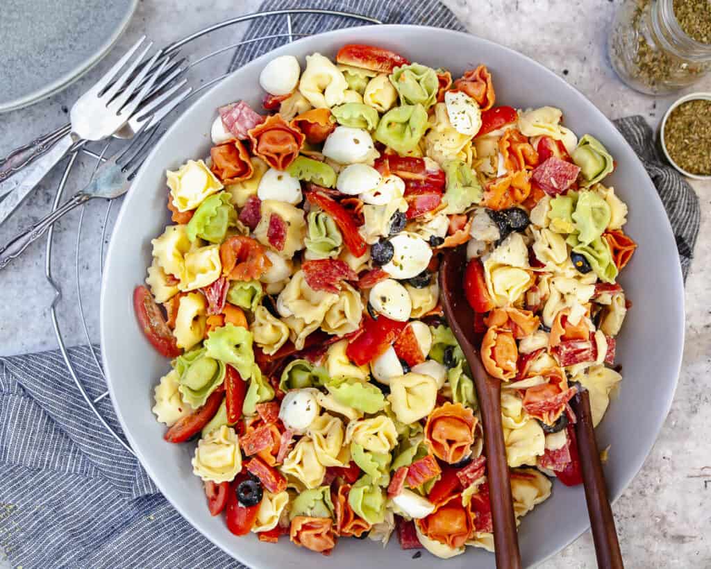 Tortellini antipasto salad in a serving bowl, with forks and plates