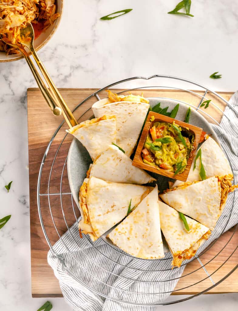Chicken tinga quesadillas plated with guacamole and shredded chicken in a bowl