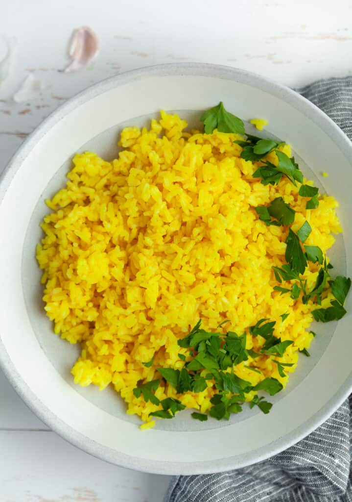 Yellow shawarma rice in a bowl, garnished with parsley