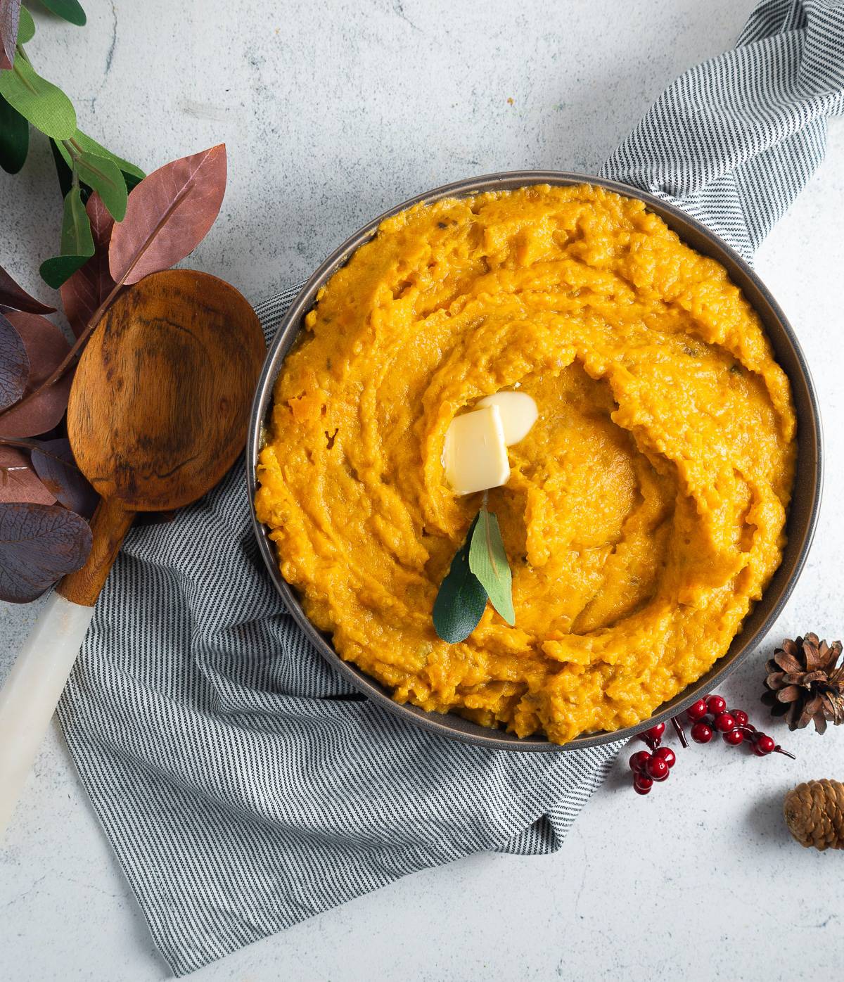 Bob evans style sweet potatoes in a bowl with butter, a serving spoon, and fall-style decor