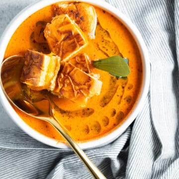 Marinara soup with grilled cheese croutons, in a bowl with a spoon