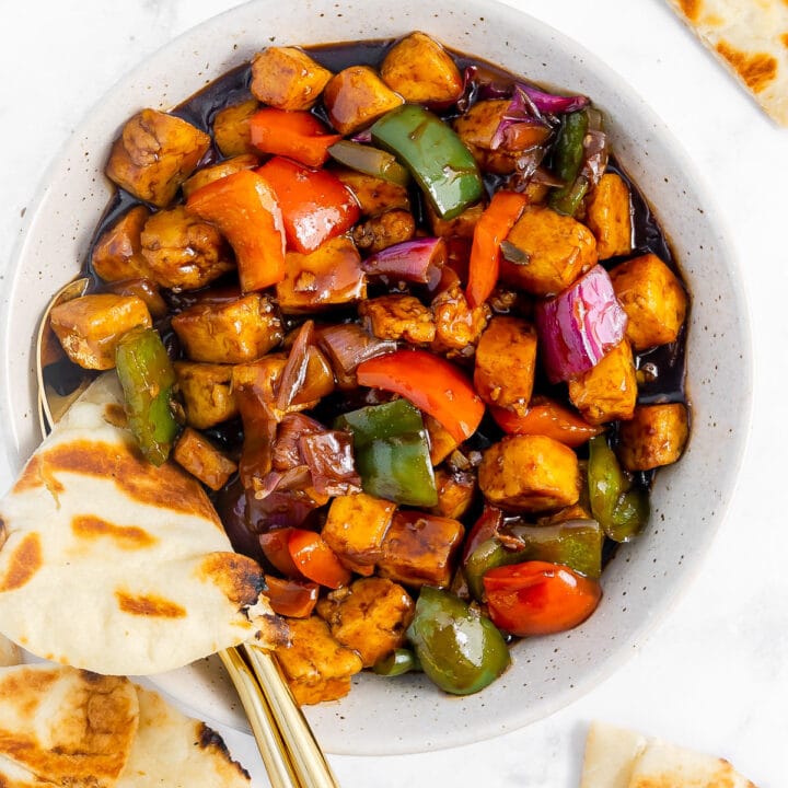 Hakka chilli paneer in a bowl, with triangles of naan