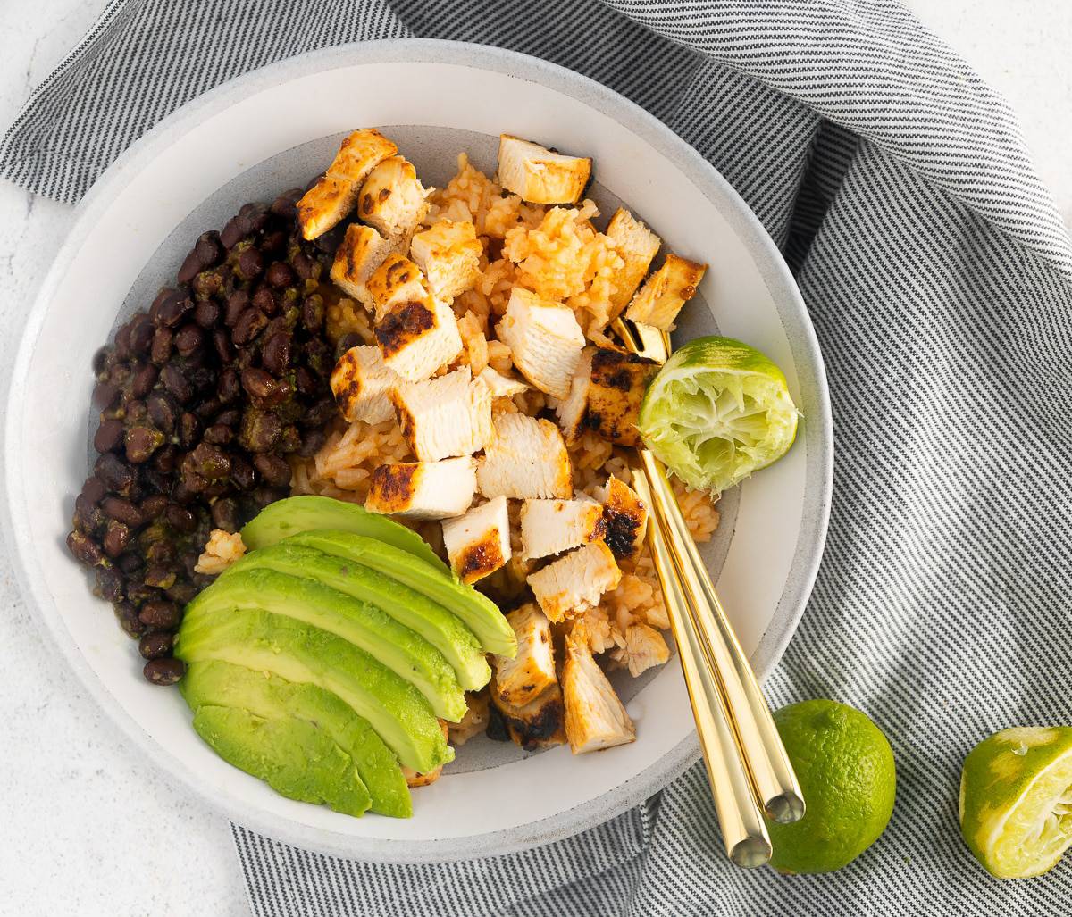 Chipotle lime chicken in a bowl with rice, beans and avocado