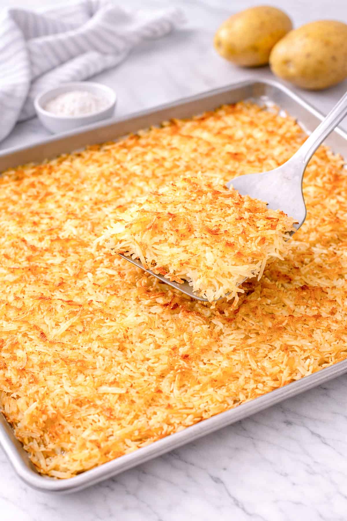 IHOP hash browns served on a sheet tray, with a spatula taking out a serving.
