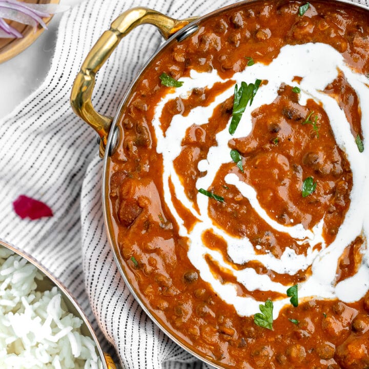 Dal makhani served in a kadai serving dish, garnished with cream.