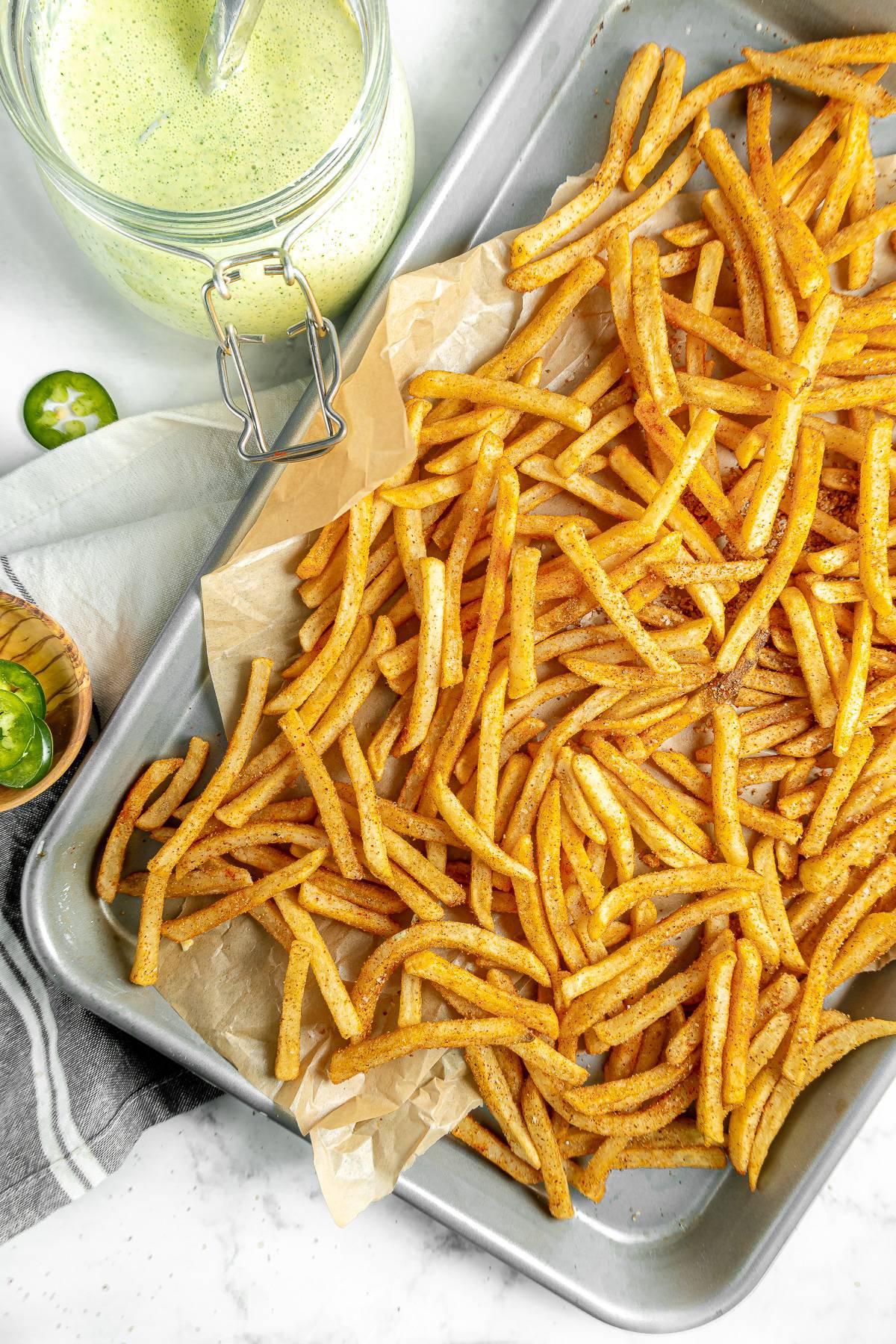 Masala fries on a sheet pan, with mint chutney on the side.