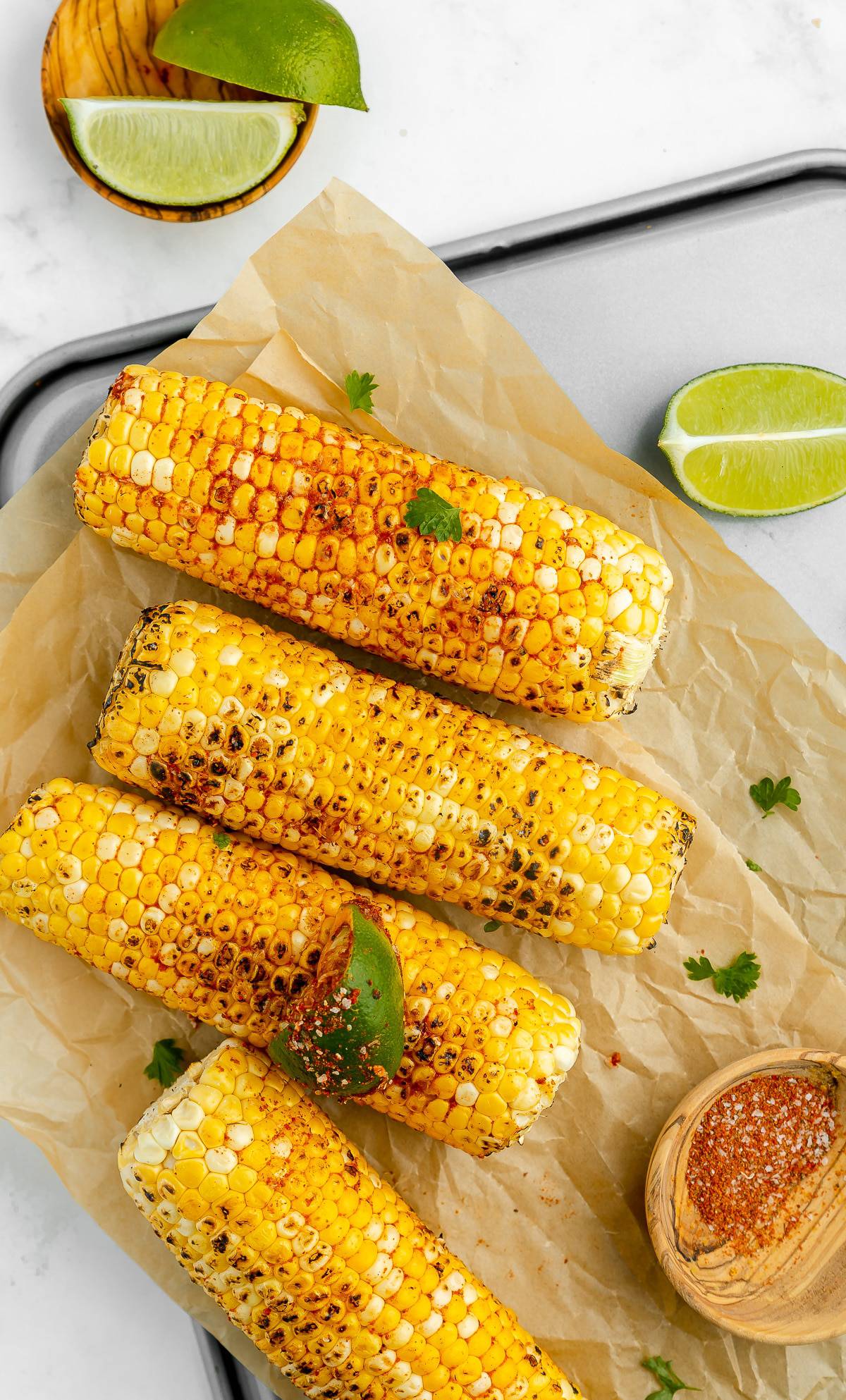 Grilled indian street corn on the cob, served with lime wedges.