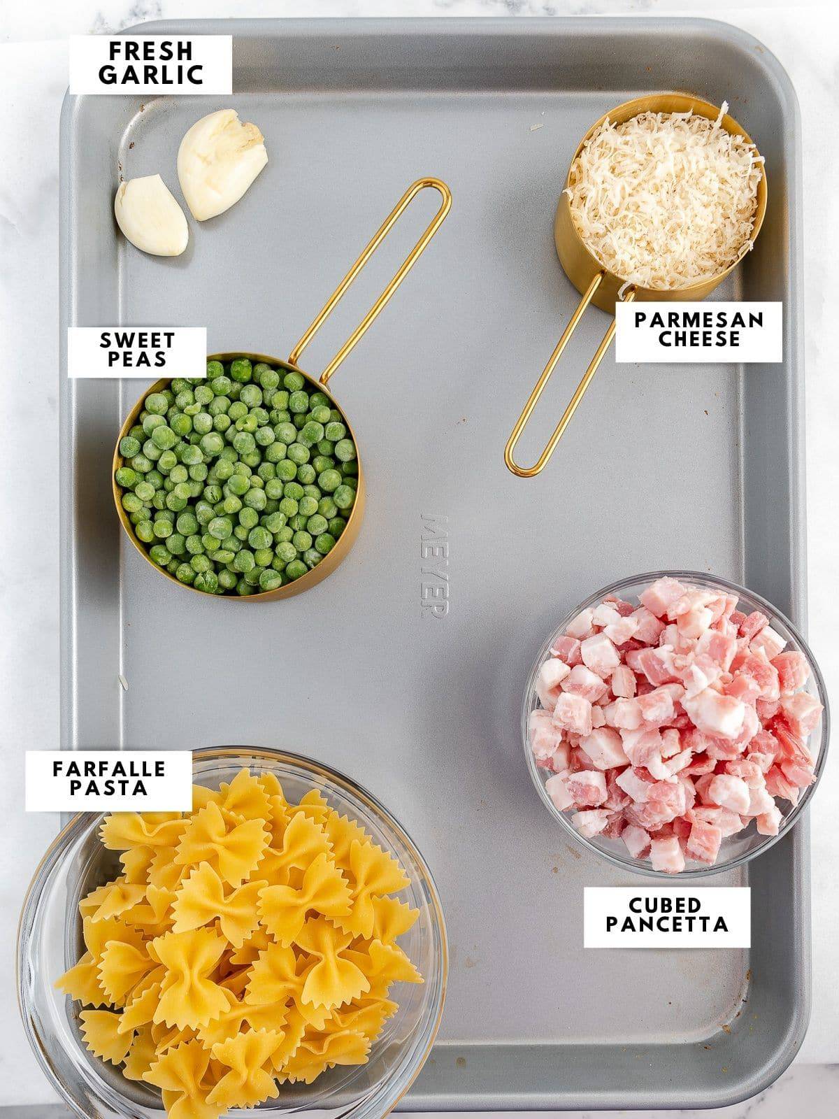 Ingredients for paste e piselli labelled on a sheet pan.
