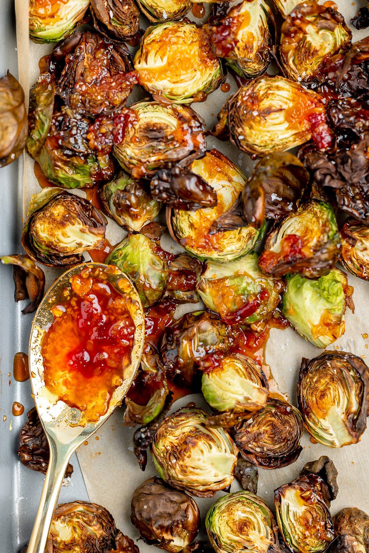 Longhorn brussel sprouts on a sheet tray with a spoon of spicy glaze.