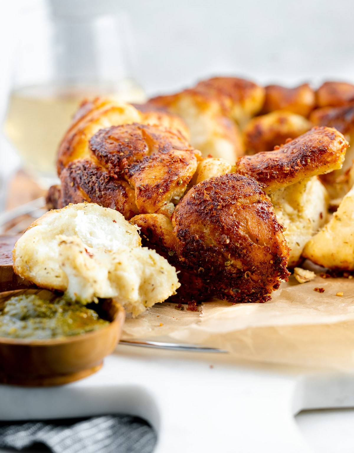Pizza dough monkey bread served on parchment paper with pesto. 