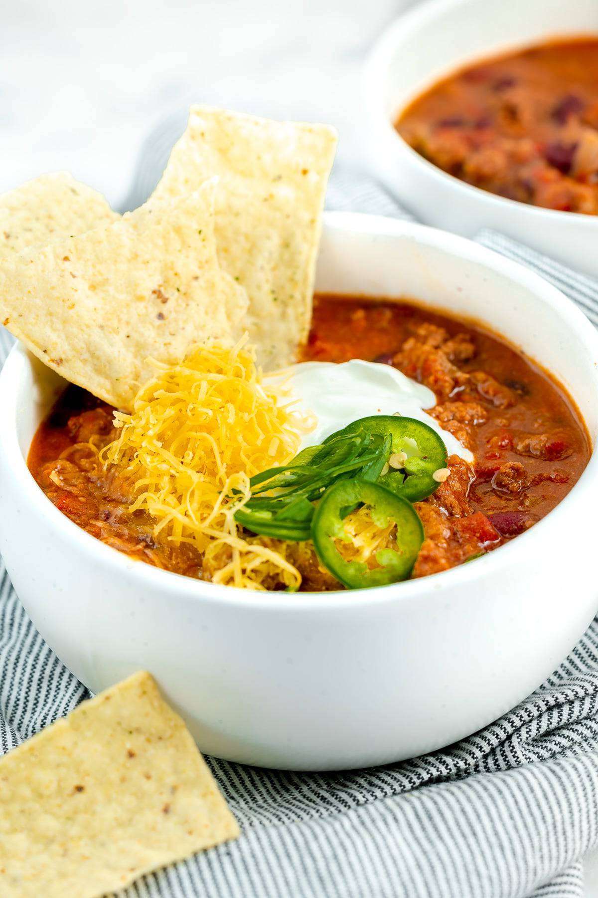Texas roadhouse chilli in a bowl, garnished with tortilla chips and fixings.