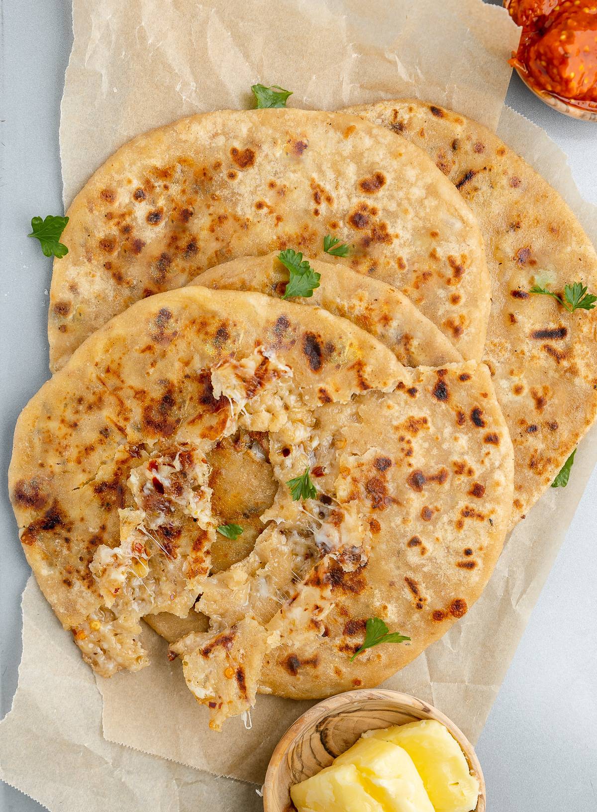 Cooked cheese parathas served on parchment paper. 