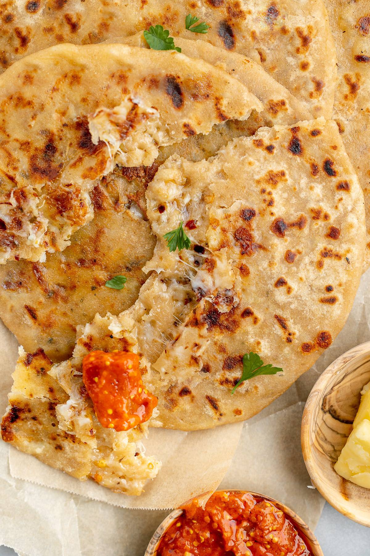 Cheese paratha torn in part, showing the melted cheese. Served with carrot pickle. 