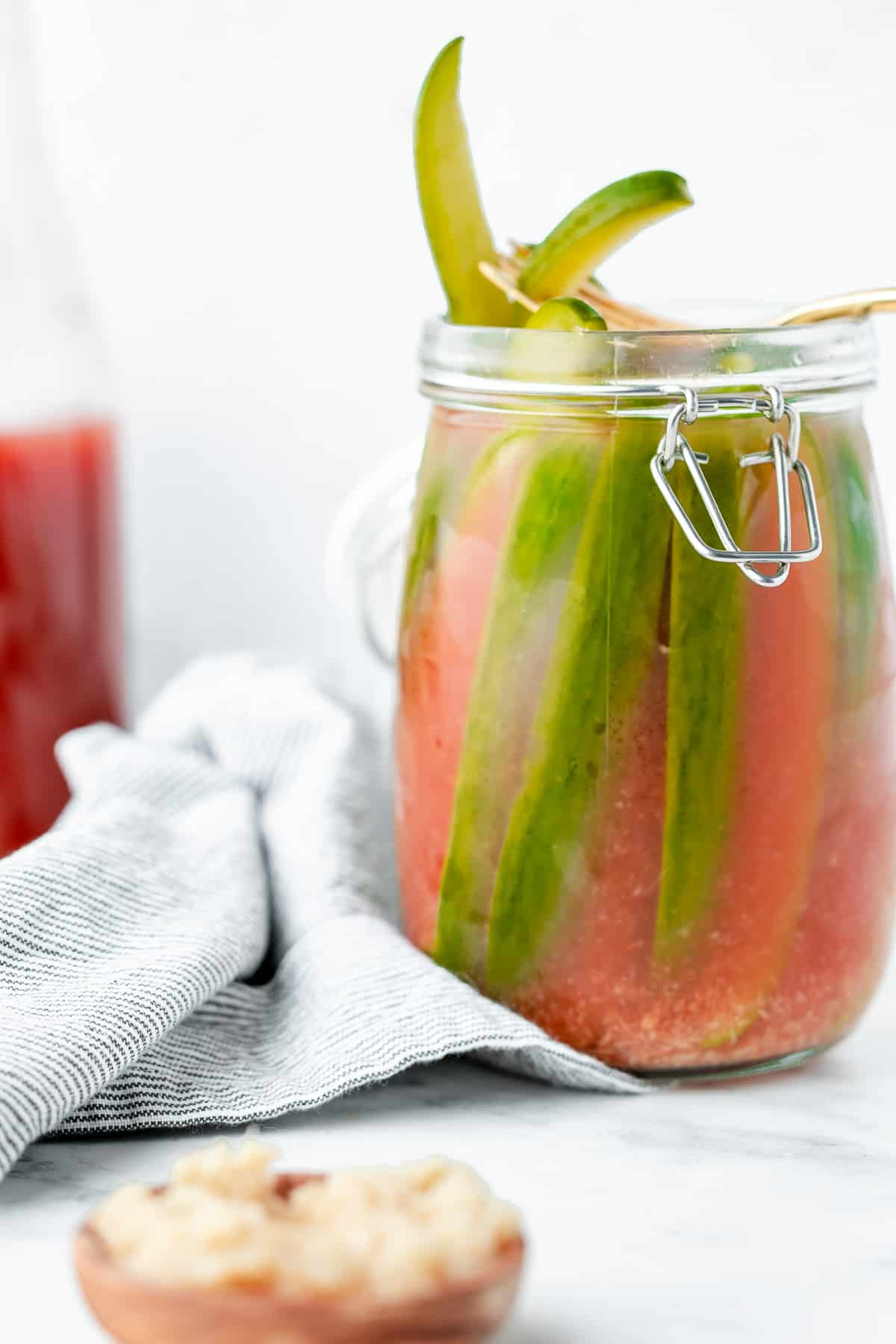 Bloody mary pickles pictured in a jar, with a fork pulling out pickles.