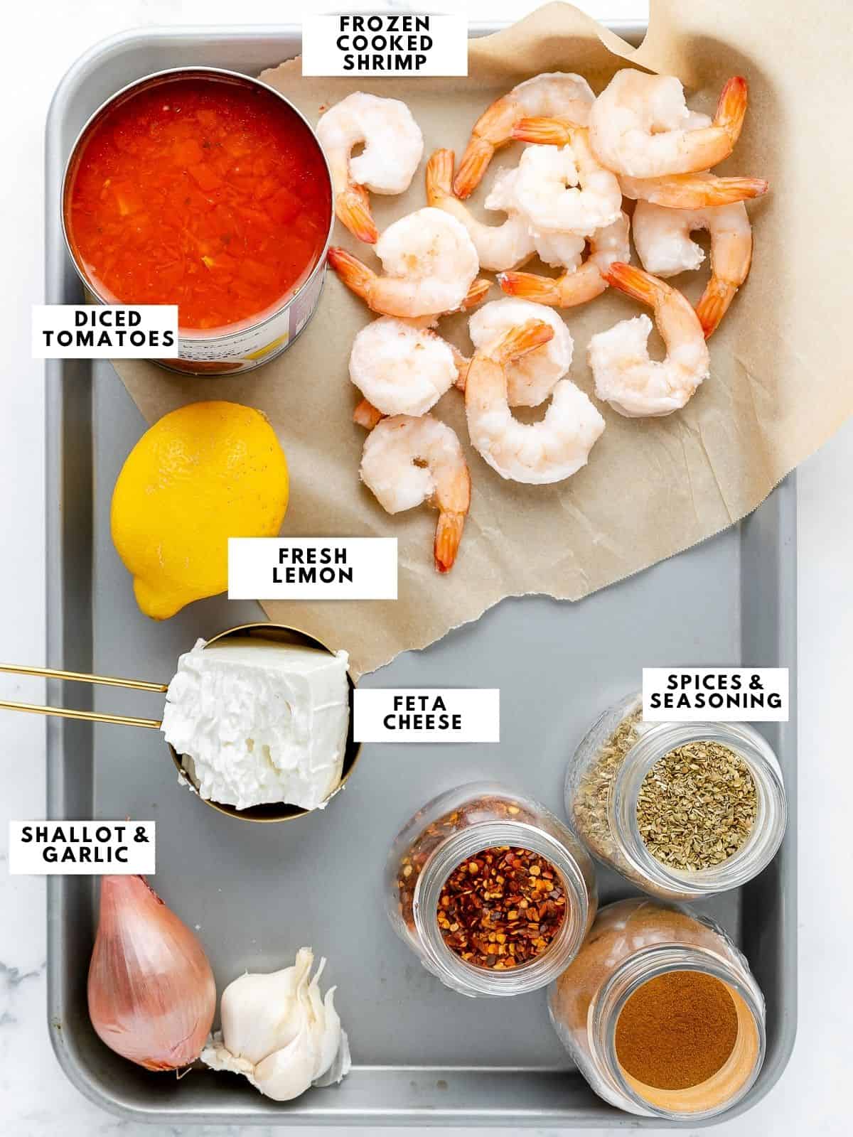Ingredients for shrimp saganaki, labelled on a sheet tray.
