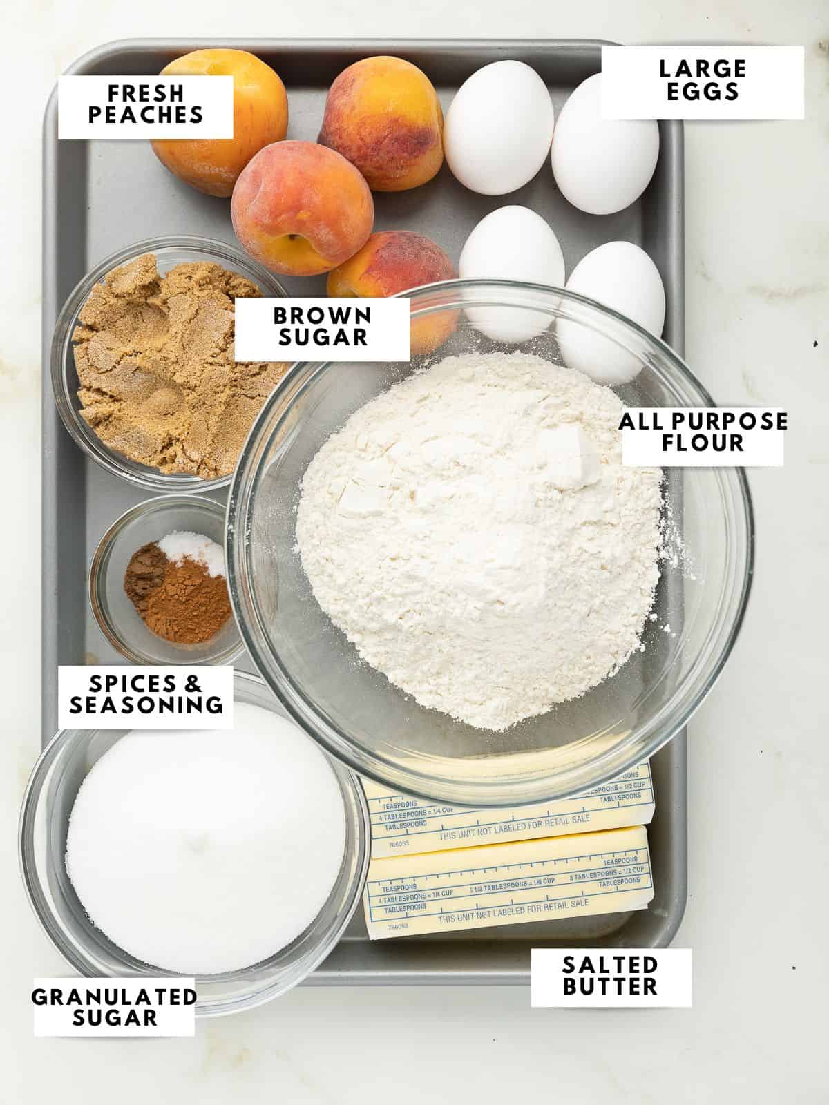 Ingredients for peach pound cake labelled on a sheet tray.