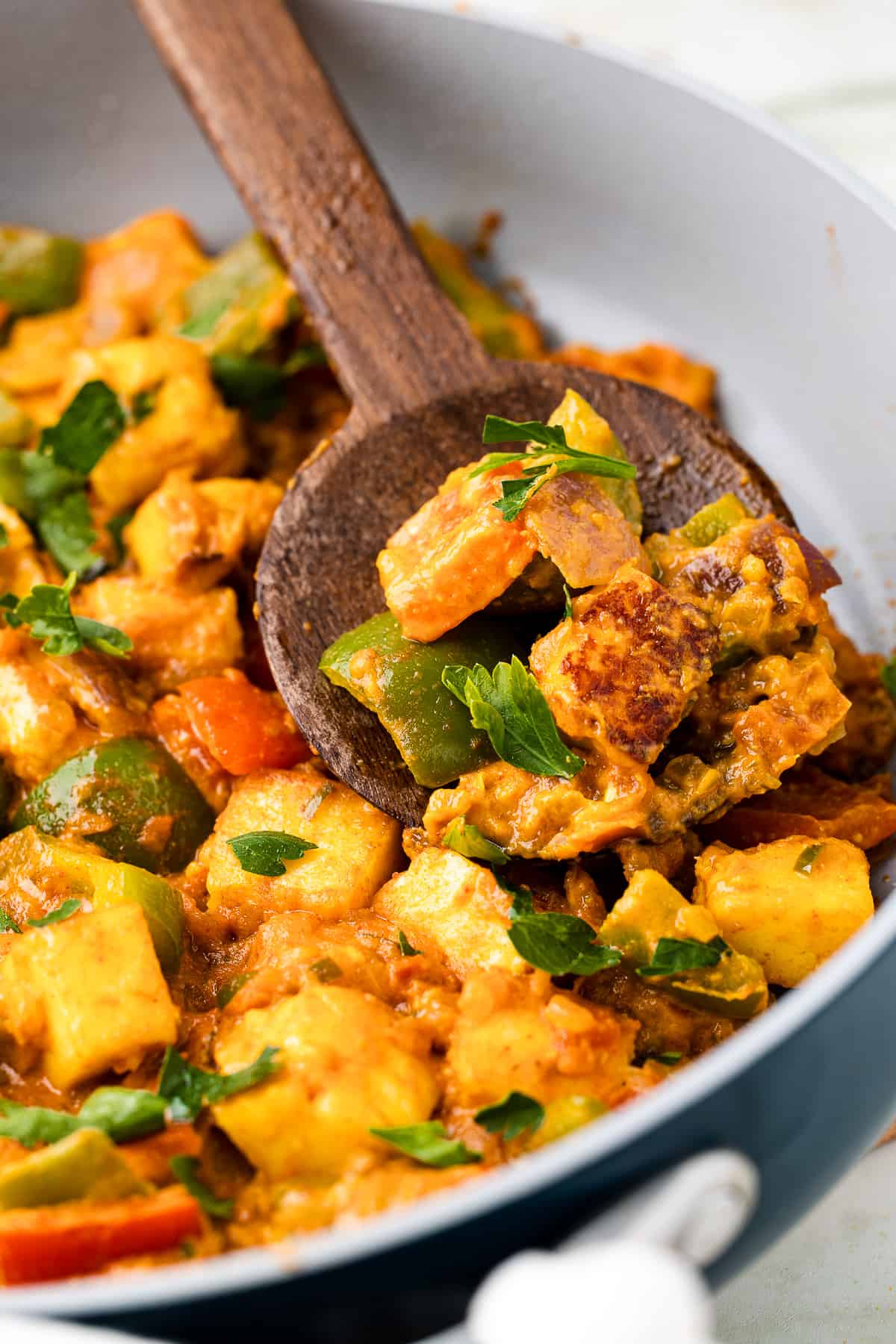 Closeup shot of kadai paneer being served on a wooden spoon. 