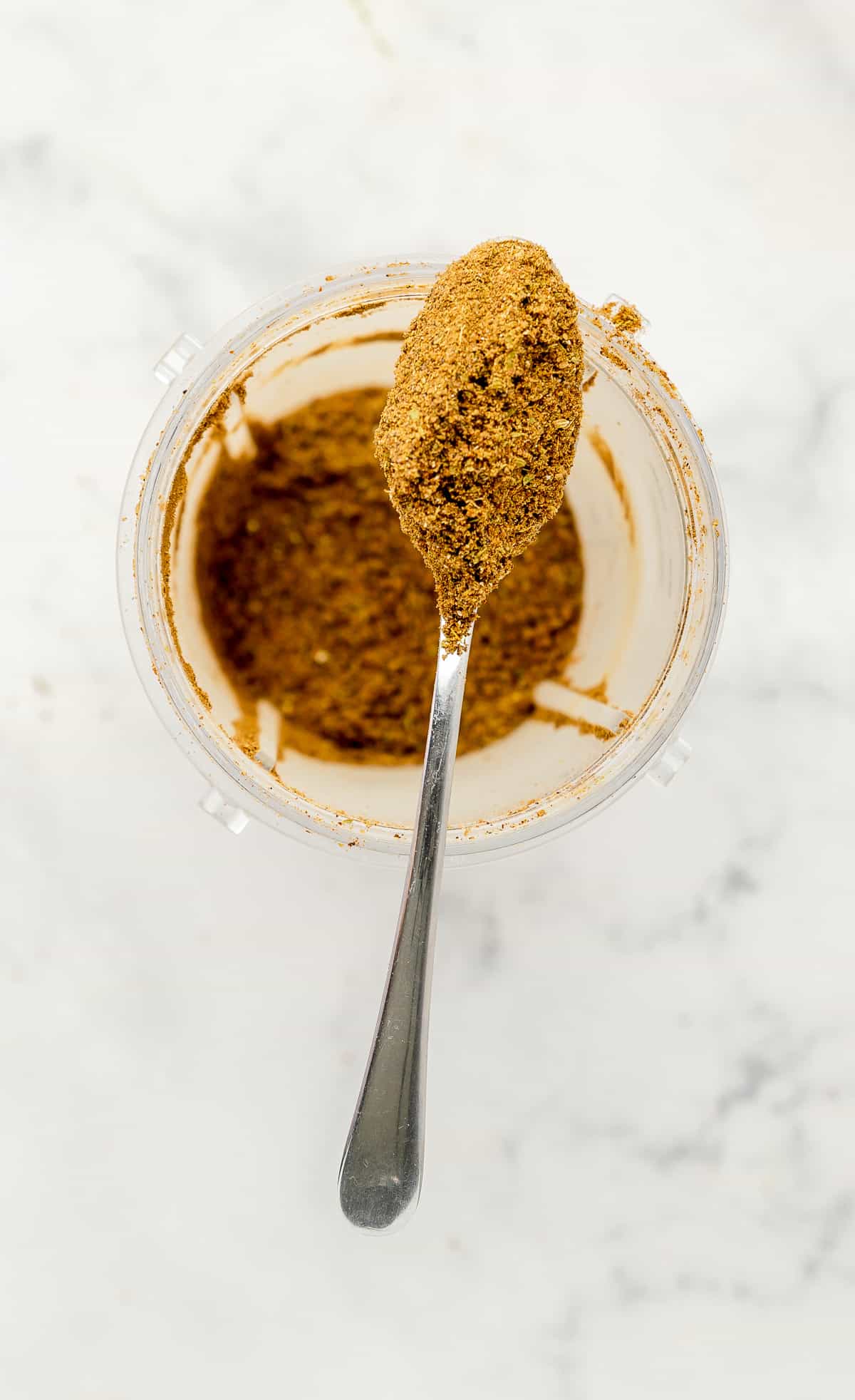 Masala powder in a blender container, with a spoon. 