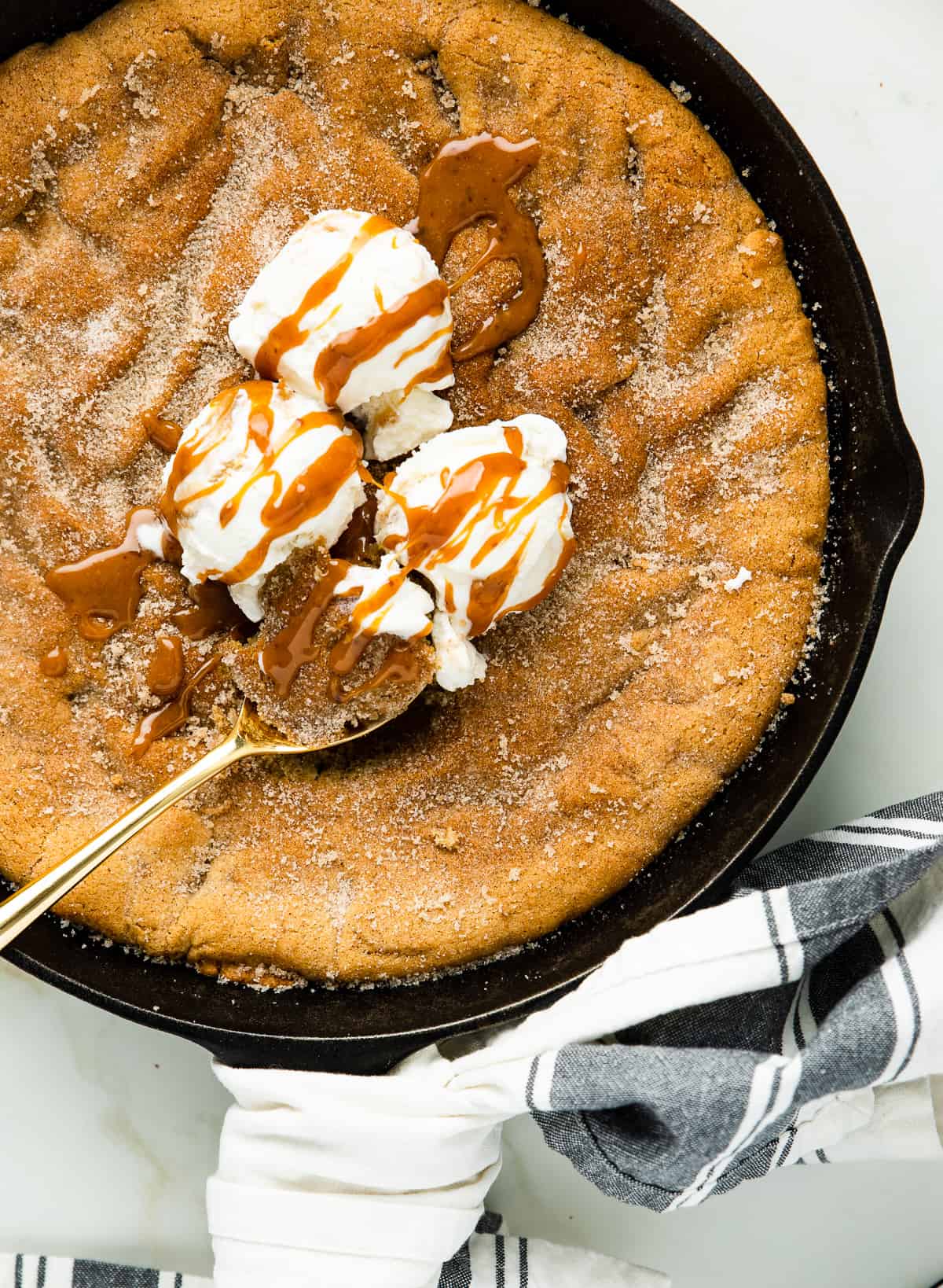 Chai Spiced Snickerdoodle Skillet Cookie with vanilla ice cream on top with caramel frizzed on the ice cream