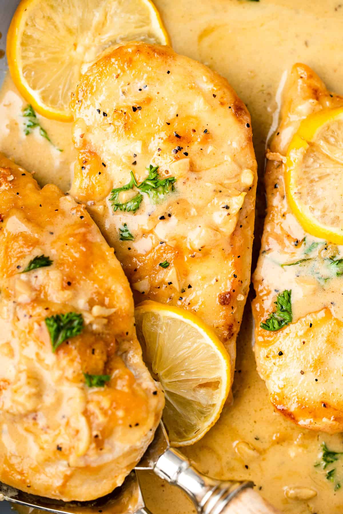 Chicken breasts in lemon sauce, garnished with fresh lemon and parsley.