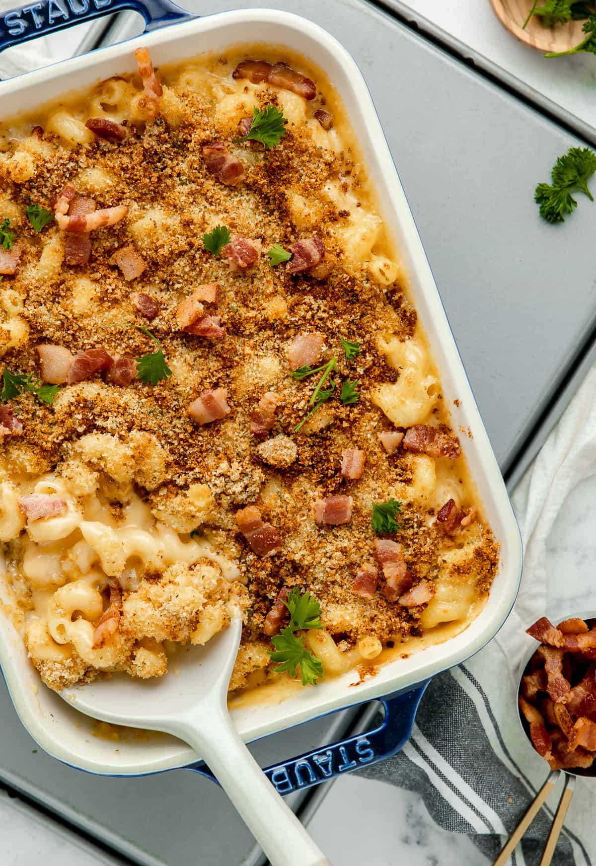Photo of mac and cheese in a baking dish, with breadcrumb topping and bacon. 