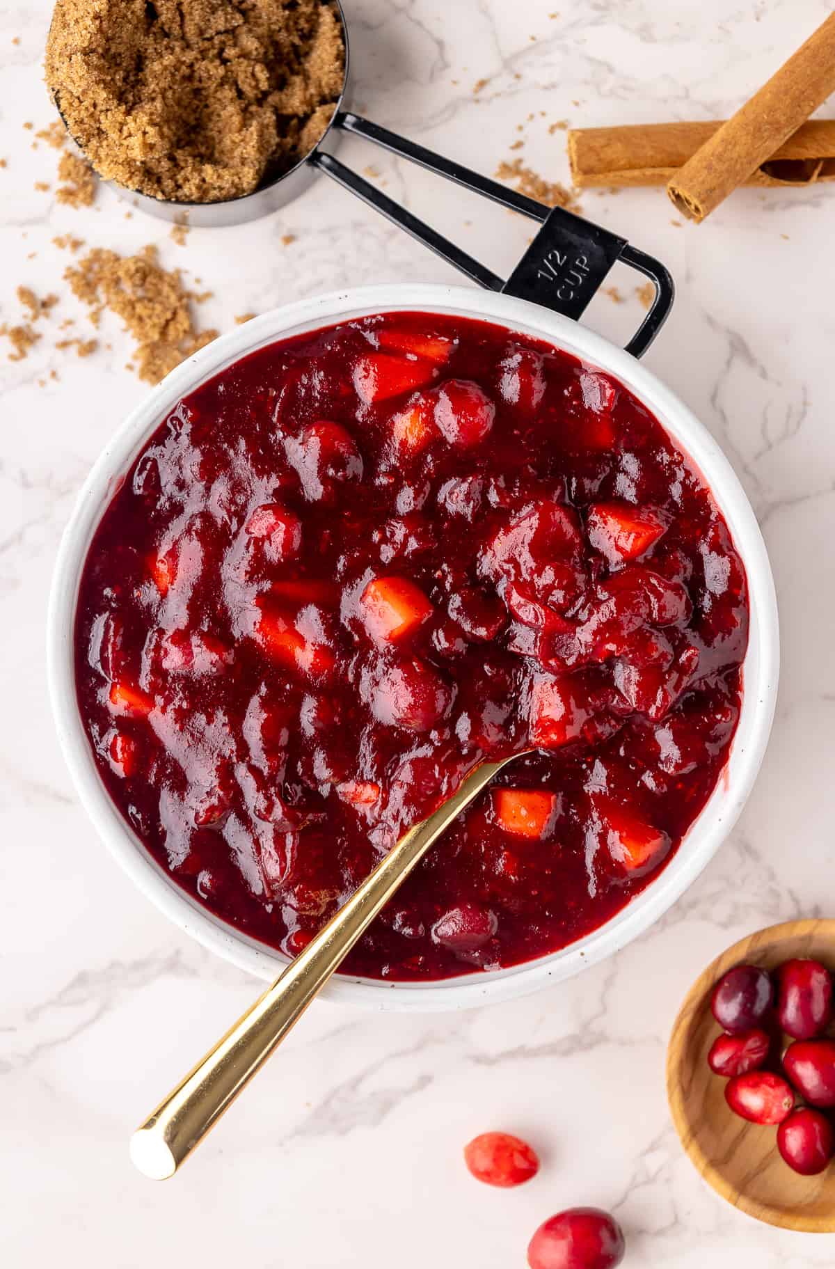 Cranberry sauce served in a bowl with a spoon. Brown sugar and cranberries as a garnish. 