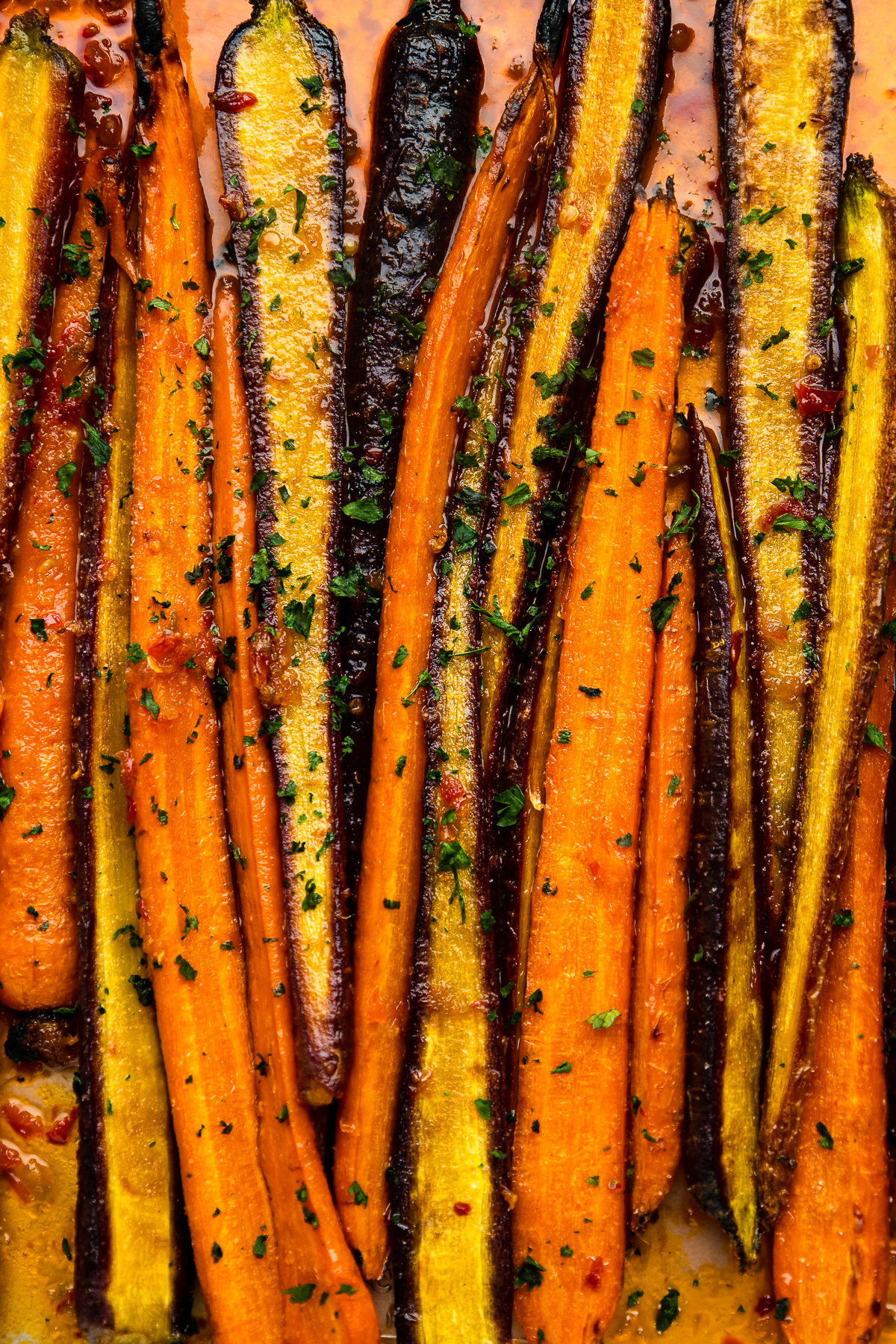 roasted carrots arranged on a sheet tray, garnished with fresh parsley.