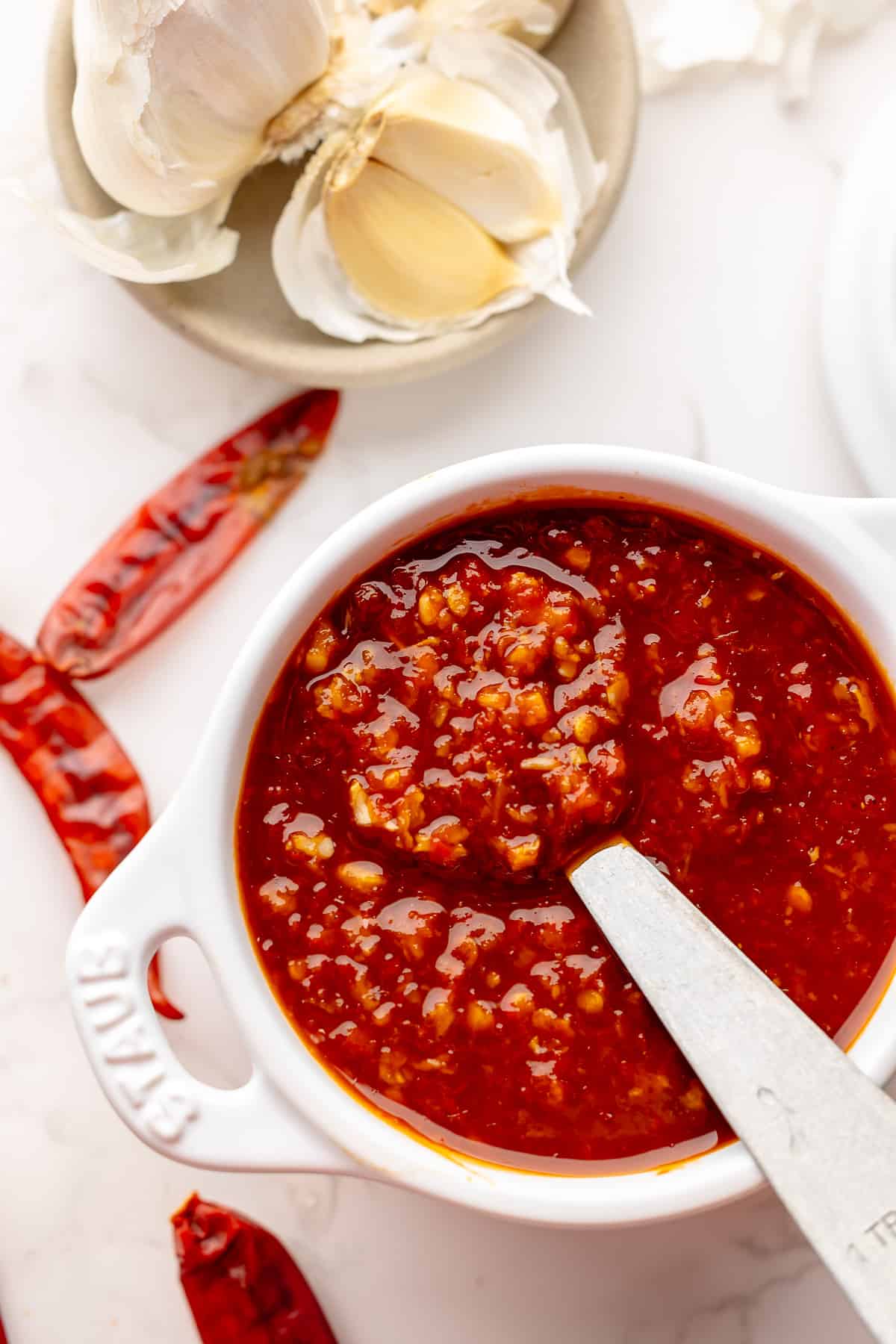 prepared chilli garlic sauce served in a small bowl, with dried chillies as a garnish.