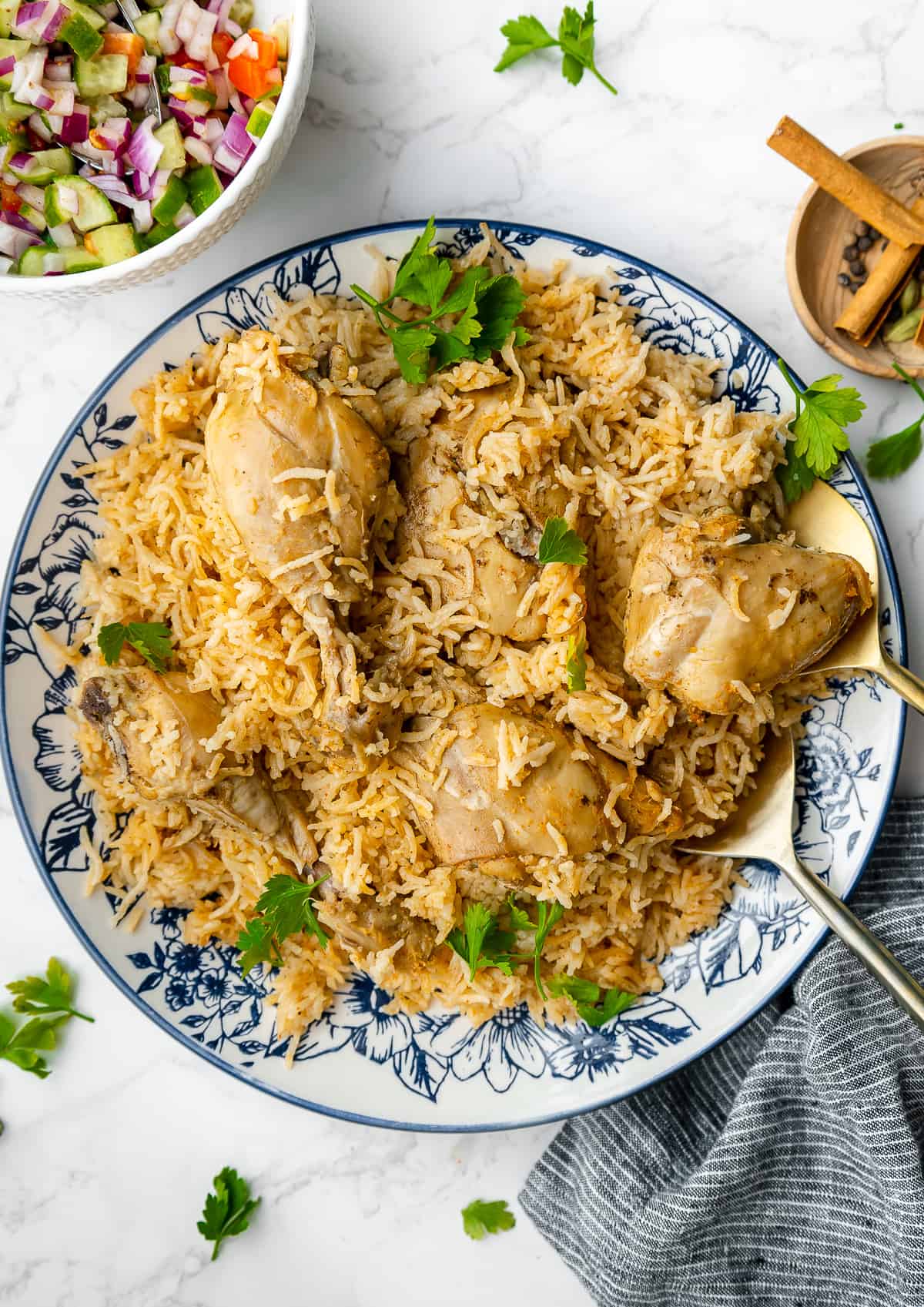 chicken pulao served on a large plate, with kachumber salad on the side.