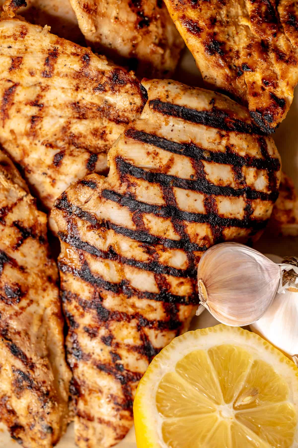 Grilled chicken breasts arranged on a sheet of parchment paper, showing cross-hatch grill marks.