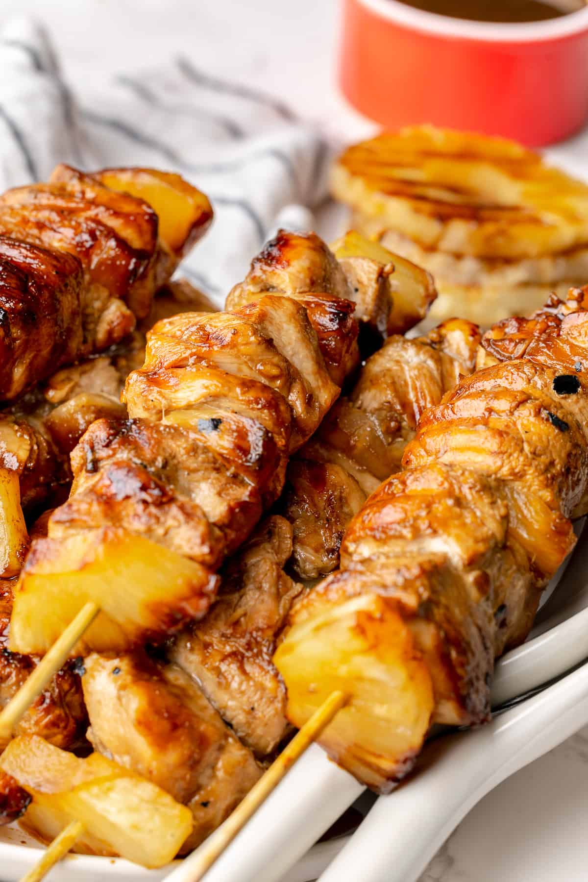 Cooked pineapple chicken teriyaki skewers on a serving plate, with two serving forks.