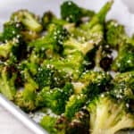 Crispy broccoli served on a parchment-lined baking sheet, sprinkled with sesame seeds.