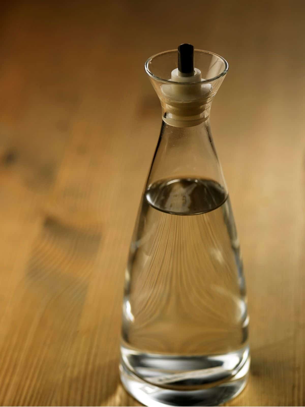 White vinegar in a bottle, placed on a table. 