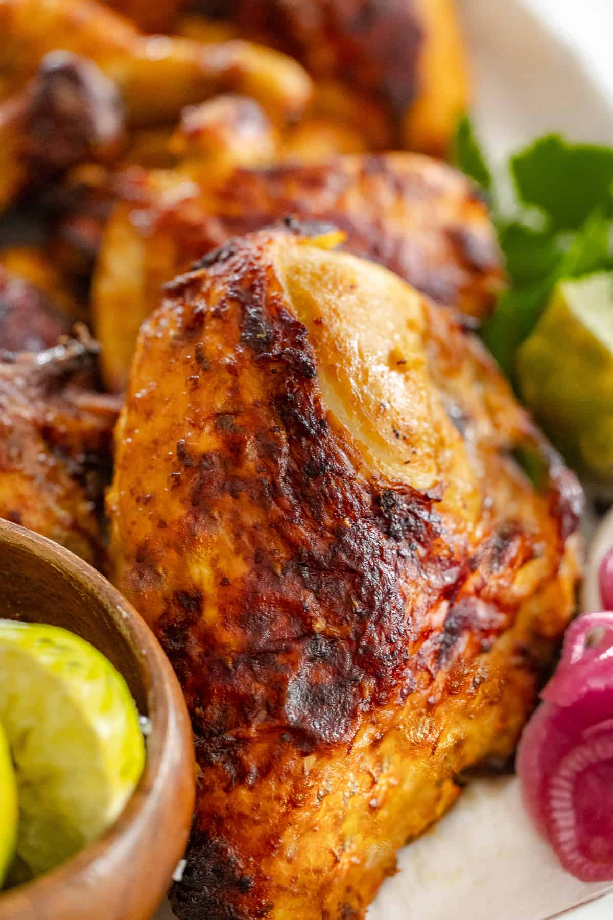 Citrus marinated grilled chicken, arranged on a platter with fresh limes and pickled red onions.