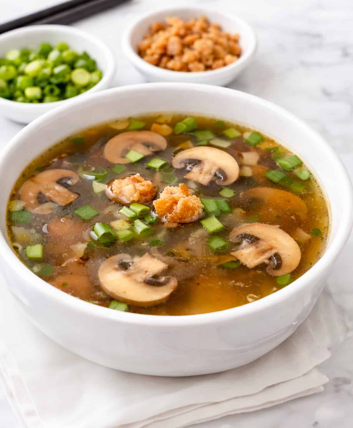 Benihana onion soup, served in a bowl topped with mushrooms and scallions.