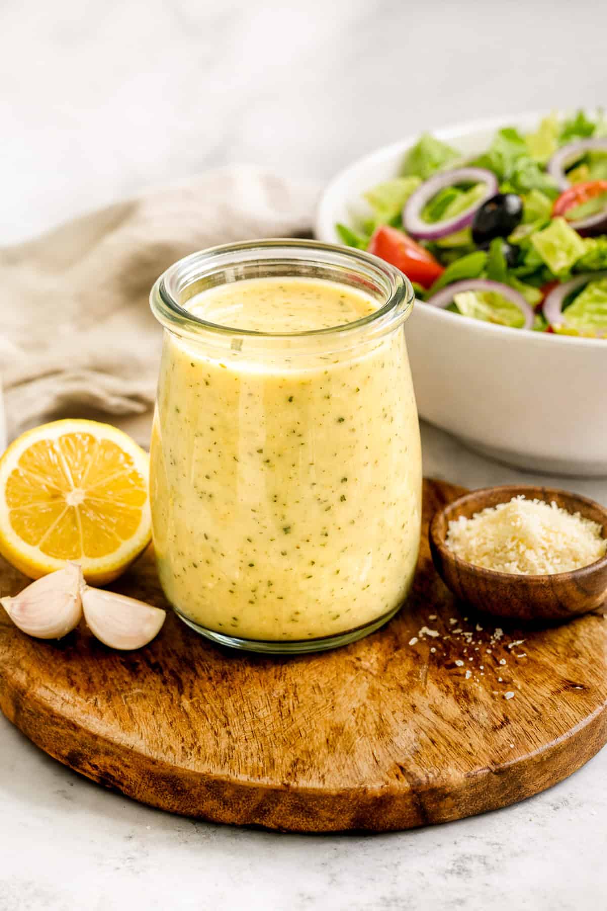 Olive Garden Salad Dressing in a jar, with garnishes of lemon, garlic, and parmesan cheese.